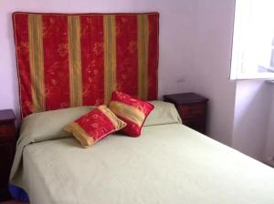 a bed with two red and gold pillows on it at lake house in Mezzanego