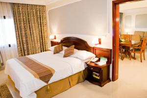 una camera da letto con un letto, un tavolo e uno specchio di Hotel Muscat Holiday a Mascate