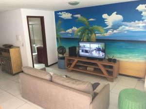 a living room with a tv and a mural of the ocean at Pipa Arara House - Por Pipa Casas de Praia in Pipa