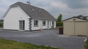 a white house with a garage and a building at Cloonboo Lodge on Wild Atlantic Way Sleeps 12 in Galway