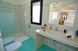 Un baño con lavabo, inodoro y espejo. en Casa Baia Azzurra, en Patù