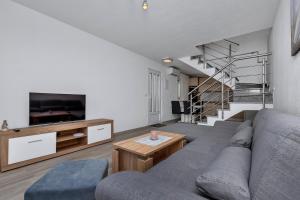 a living room with a couch and a tv and stairs at Apartmani R&B Radalj in Makarska