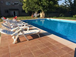 a row of lounge chairs next to a swimming pool at Hostal Expo in Porriño