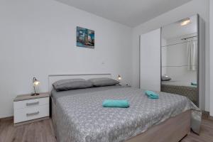 a white bedroom with a bed and a mirror at Apartmani R&B Radalj in Makarska