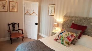a bedroom with a bed and a chair and a door at The Old Manse in Lowick