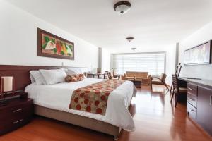 a bedroom with a large bed and a living room at Hotel Cuellars in Pasto