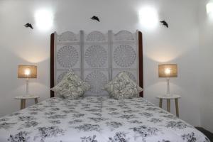 a bedroom with a large bed with two lamps at Casa da Muralha Suíte in Monsaraz