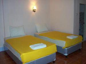 two beds in a room with yellow sheets at D's Corner & Guesthouse in Phuket Town
