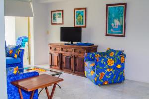 a living room with a tv and two chairs and a table at ENNA INN IXTAPA DEPARTAMENTOS ViSTA AL MAR in Ixtapa
