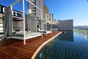 a row of beds on the edge of a swimming pool at Sonata Hotel Puebla Angelópolis Distrito Sonata in Puebla