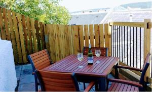 a wooden table with two glasses of wine on a patio at Brae Cottage, Inverness in Inverness