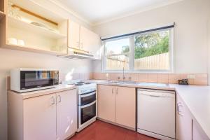 a kitchen with a stove, sink, microwave and refrigerator at Nightcap at Ferntree Gully Hotel Motel in Fern Tree Gully