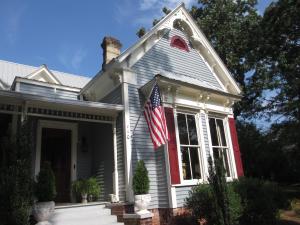 Una casa blanca con una bandera americana. en Adair Manor Bed & Breakfast, en Adairsville