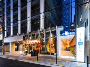 un edificio en una calle de la ciudad por la noche en HOTEL UNIZO Osaka Shinsaibashi, en Osaka