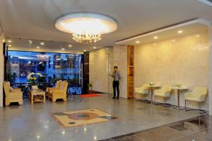 um homem de pé em um lobby com uma mesa e cadeiras em Full House Hotel em Nha Trang