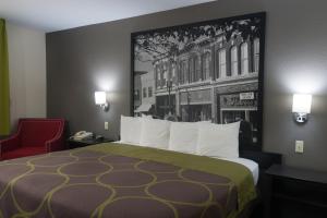 une chambre d'hôtel avec un lit et un fauteuil rouge dans l'établissement Super 8 by Wyndham Arkansas City KS, à Arkansas City