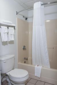 y baño blanco con aseo y ducha. en Super 8 by Wyndham Arkansas City KS, en Arkansas City