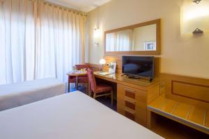 a hotel room with a bed and a desk with a television at Best Western Hotel I Triangoli in Casal Palocco
