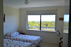 two beds in a room with a large window at Surinam in Dunsborough