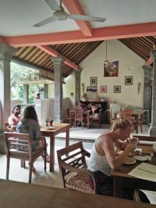 a woman sitting at a table in a restaurant at Nyuh Gading Accommodation Ubud in Ubud