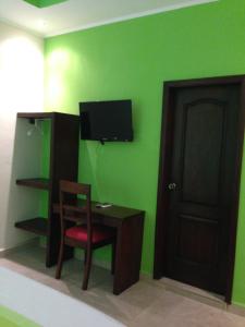 a room with a green wall with a desk and a television at Hotel Boutique Casa D' Luna in Choluteca