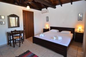 a bedroom with a bed and a table and a chair at Arsinoi Stonehouses in Limenaria