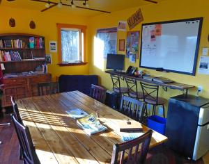 a room with a table and chairs and a large screen at Wanderer's Inn Backpackers Hostel in Haines Junction