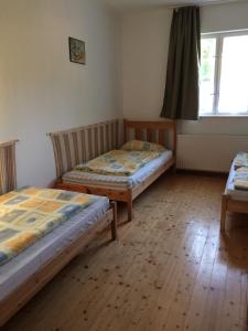 two beds in a room with wooden floors and a window at Fasor vendégház in Balatonszemes