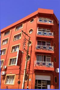 un grand bâtiment rouge avec des fenêtres et des balcons. dans l'établissement Hotel Le Relais Normand, à Antananarivo