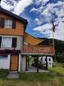 uma casa com um deque de madeira e uma bandeira em La Bola em Roveredo