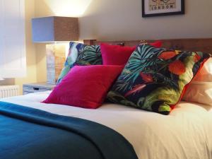 a bed with colorful pillows on top of it at Havisham House in Woburn