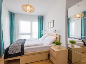 a bedroom with a bed with blue curtains and a window at VacationClub - Przy Plaży Apartment 10 in Mielno
