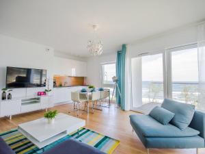 a living room with a blue couch and a table at VacationClub - Przy Plaży Apartment 10 in Mielno