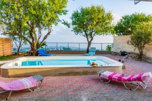 a swimming pool with two lawn chairs next to it at Le Paradis d' Elli in Lakíthra