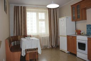 a kitchen with a table and a white refrigerator at Апартаменты на Пермякова in Tyumen