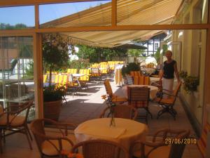 a woman standing on a patio with tables and chairs at Hotel Drei Kronen in Tecklenburg