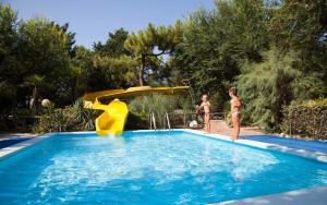 two girls standing next to a pool with a slide at Holiday Center Valdor in Cavallino-Treporti +20 photos