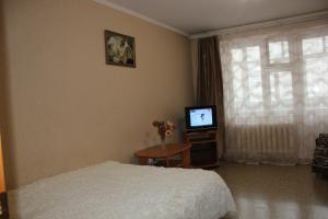 a bedroom with a bed and a tv and a window at Апартаменты на Пермякова in Tyumen