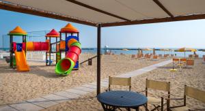 un parco giochi sulla spiaggia con sedie e tavolo di Hotel Riviera a Bellaria-Igea Marina