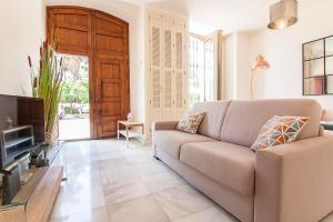 Una sala de estar con un sofá y un televisor. en Cortina Apartments !, en Málaga