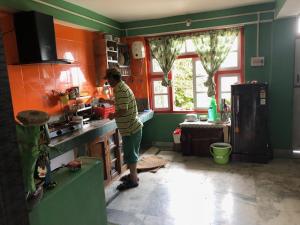 un uomo in piedi in una cucina che prepara il cibo di Vamoose Soshing Homestay a Ravangla