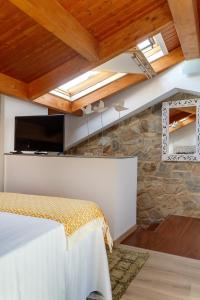 1 dormitorio con pared de piedra y techo con tragaluz. en Numa Rúa Travesa en Santiago de Compostela