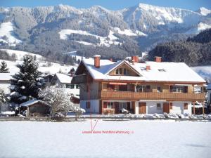une maison dans la neige avec des montagnes en arrière-plan dans l'établissement Hornerblick, à Sonthofen