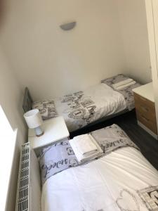 two beds in a small room with a night stand and a bedskirts at Bournemouth Hot Tub & Sauna Holiday Let in Bournemouth