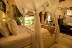een slaapkamer met een hemelbed bij Scallywags Beach Club in Gili Air