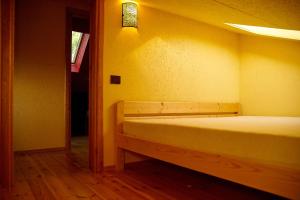 a bed in a room with a yellow wall at Akmeninis Bebras in Zhemoytele