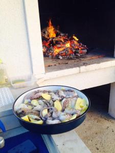 una sartén de comida frente a un horno de fuego en Villa Bella Vista, en Lumbarda
