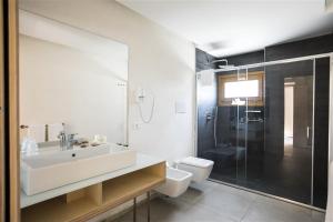 a bathroom with a sink and a toilet and a shower at Cave Bianche Hotel in Favignana