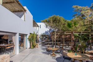 Un patio al aire libre con mesas, sillas y árboles. en Sa Cala Suites, en Es Caló