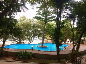 a large blue swimming pool in a park with trees at The C Samet Beach Resort SHA Plus in Ko Samed